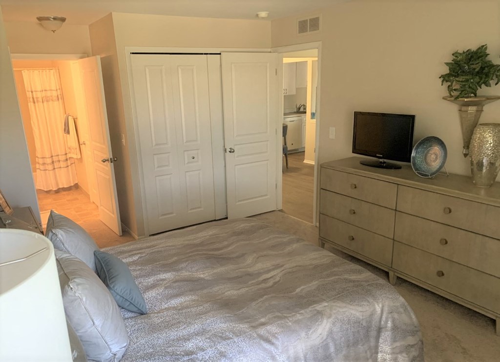 a bedroom with a bed and a dresser with a tv