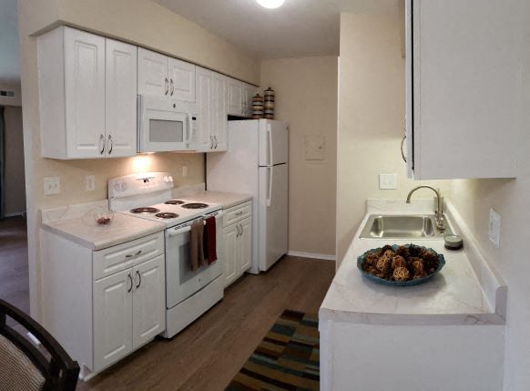 a kitchen with white cabinets and a sink and a refrigerator
