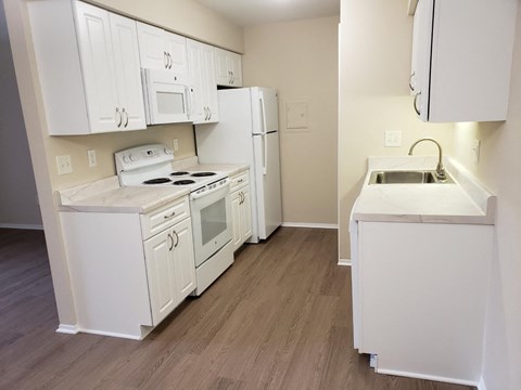 a kitchen with white cabinets and appliances and a sink and a refrigerator