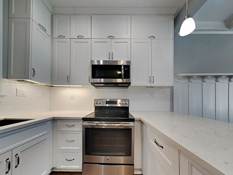 a white kitchen with stainless steel appliances and white cabinets