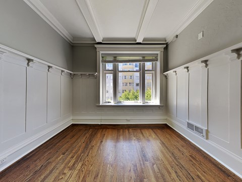 an empty room with wood floors and a window
