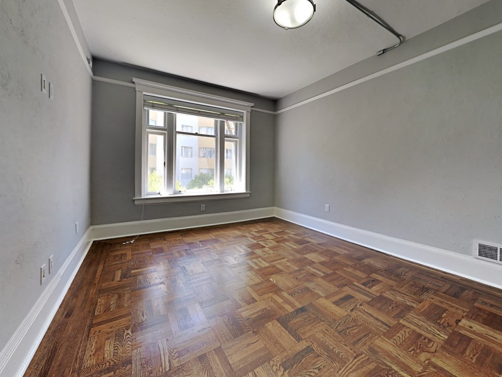 an empty living room with wood flooring and a window
