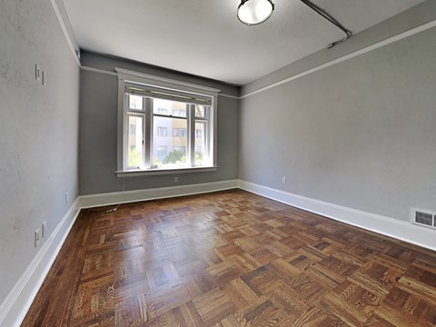 an empty living room with wood flooring and a window