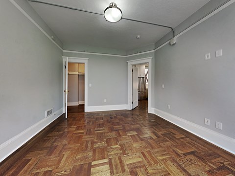 an empty living room with wood flooring and grey walls