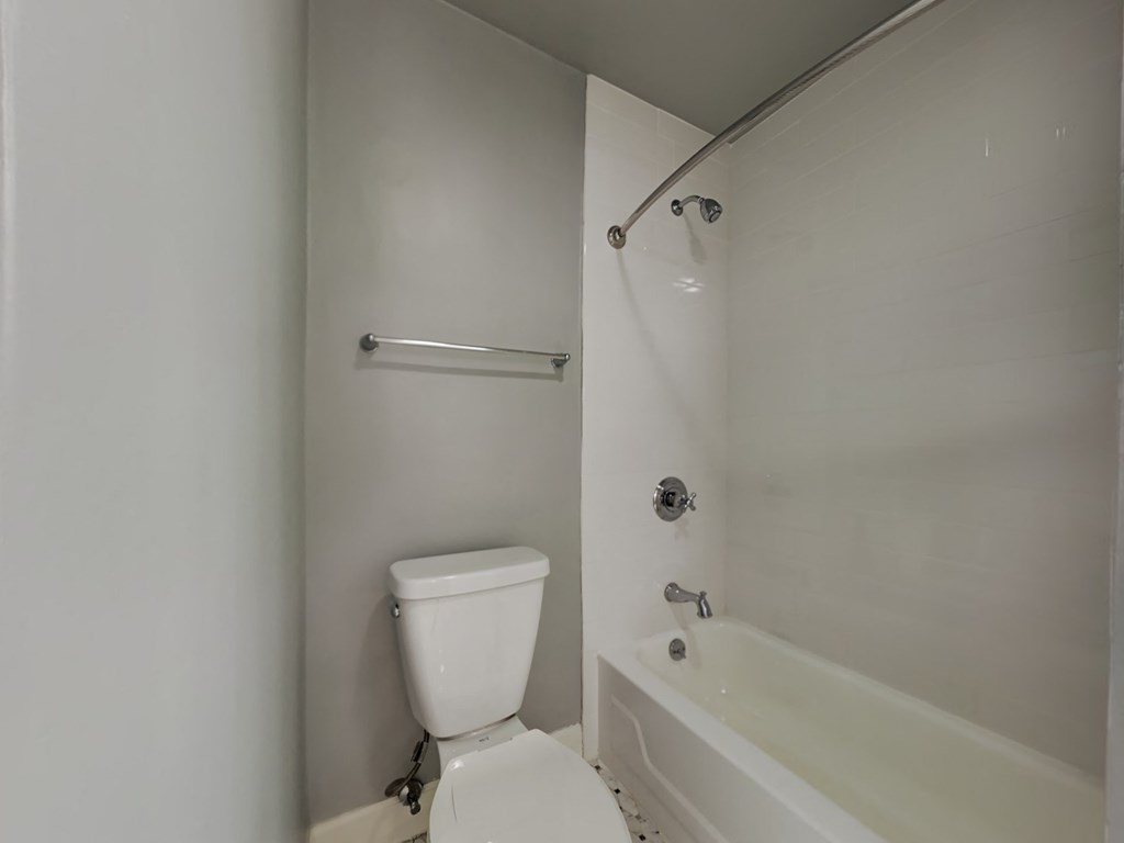 a white bathroom with a white toilet and a bath tub