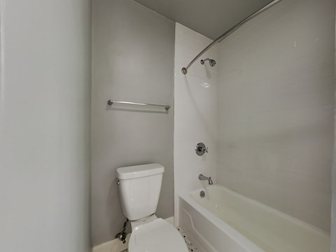 a white bathroom with a white toilet and a bath tub