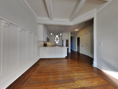 a kitchen and living room with white walls and wood floors