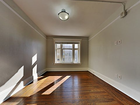 an empty living room with wood floors and a window
