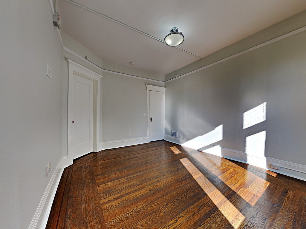 an empty living room with wood floors and white walls