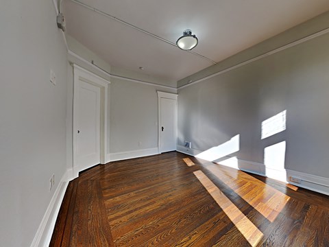 an empty living room with wood floors and white walls
