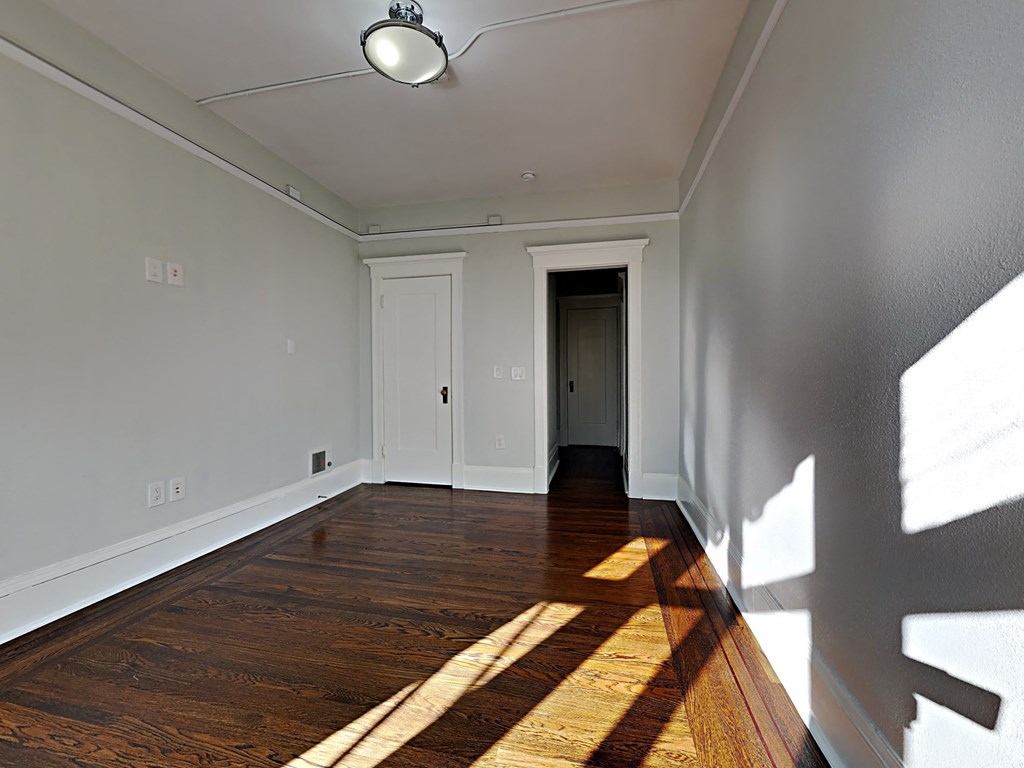 an empty living room with wood floors and white walls