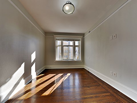 an empty living room with wood floors and a window