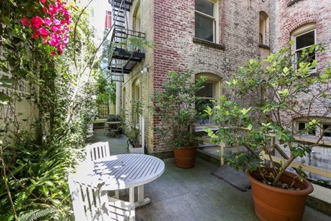 a small patio with a white table and chair and potted plants