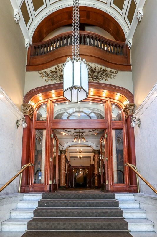 the lobby of a building with stairs and a chandelier