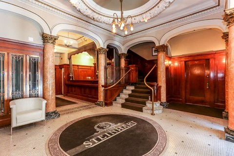 the lobby of a building with stairs and a carpet in the center of the floor