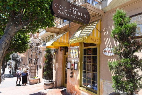 people walking down a street in front of a restaurant