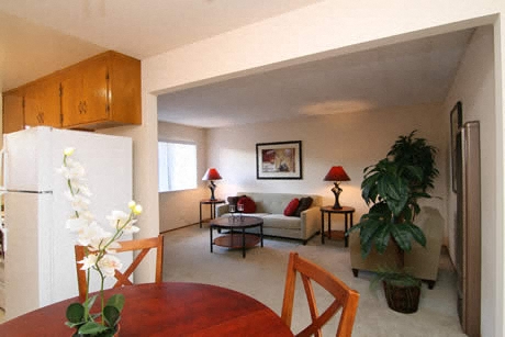 a living room and dining room with a table and a refrigerator