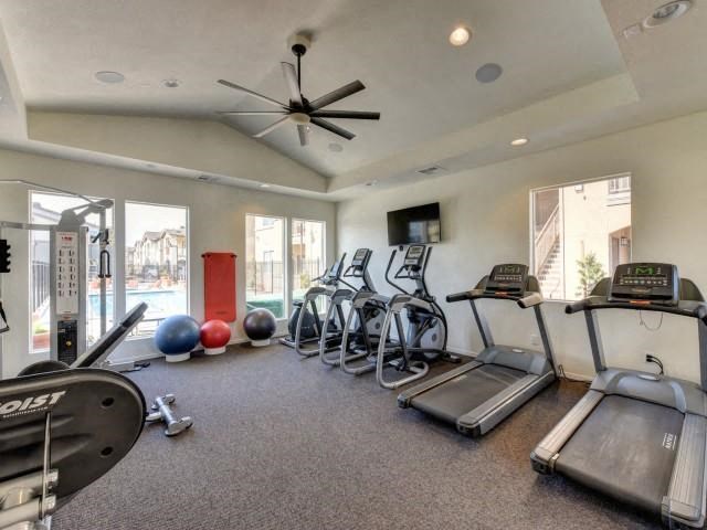 a gym with cardio equipment and a ceiling fan