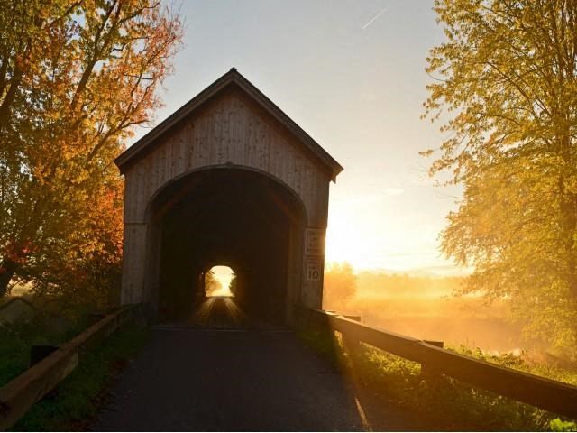 a covered bridge with the sun shining through it