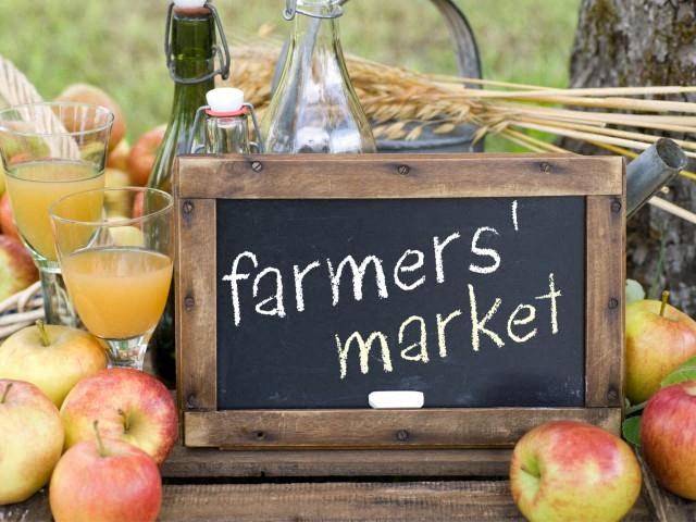 a farmers market sign on a table with apples