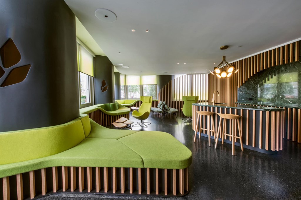 a lounge area with green couches and chairs and a table