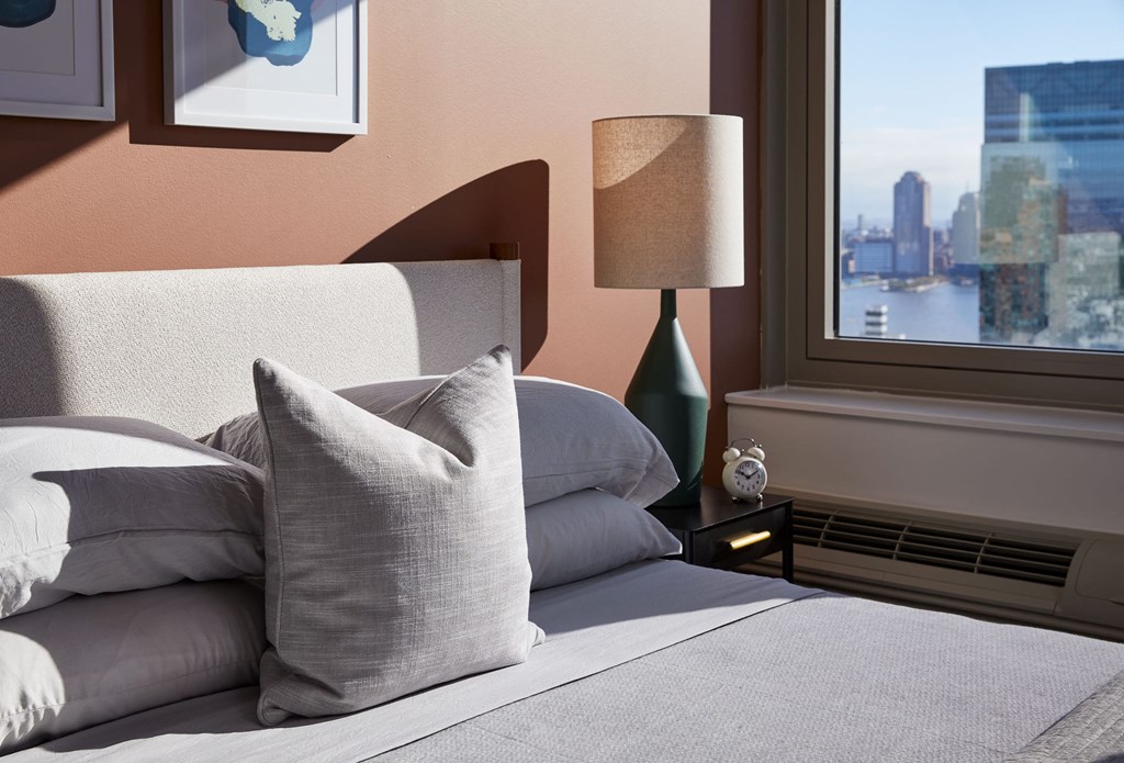 a bed with pillows and a lamp in a room with a window