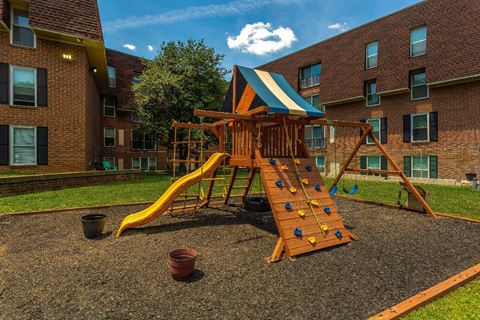 a playground with a swing set in front of an apartment building