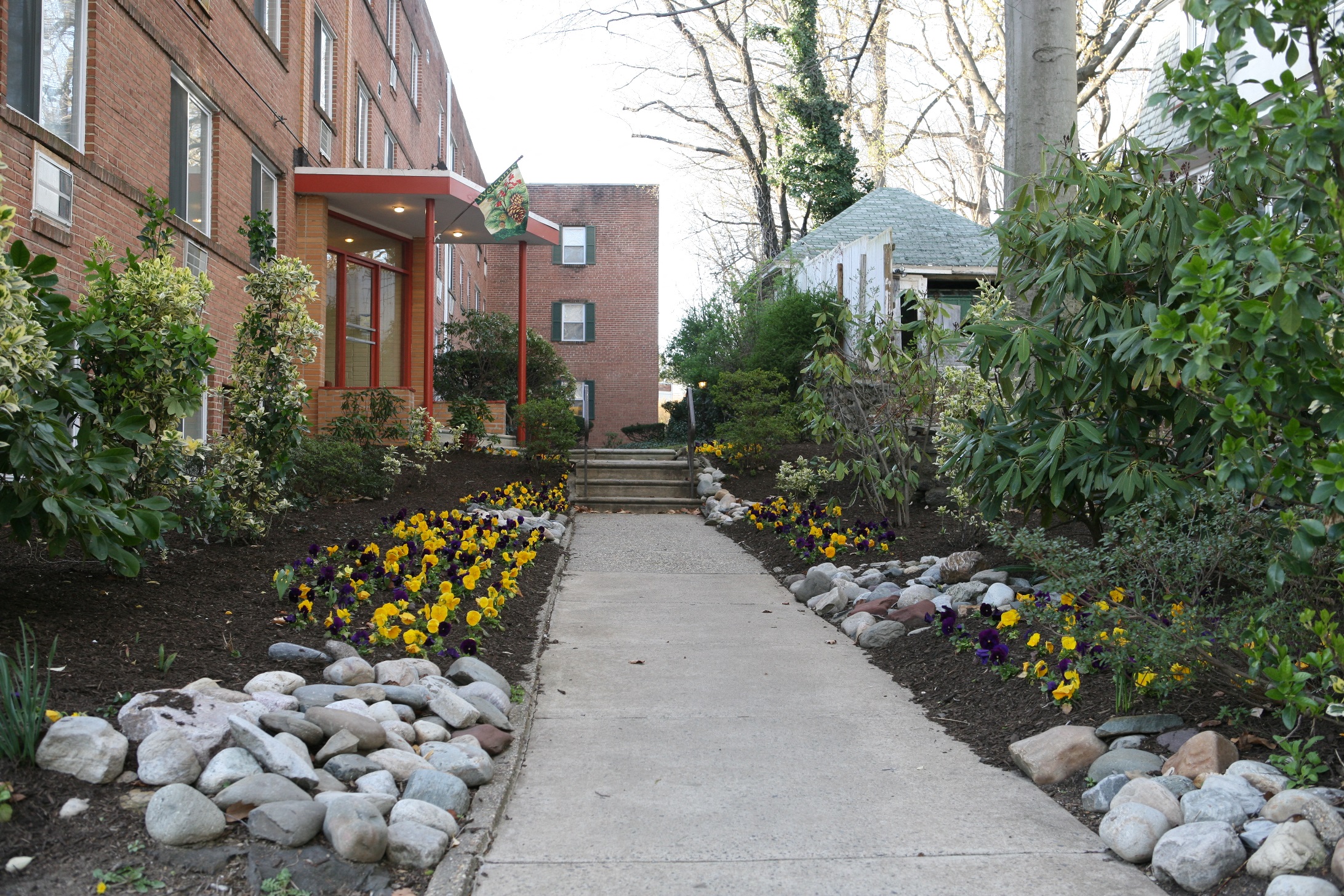 Exterior of building showing entrance, walkway, and gardens.