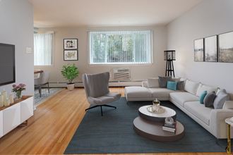 Living room with wood flooring, beige walls, and air conditioning unit under windows. Opens to dining room.