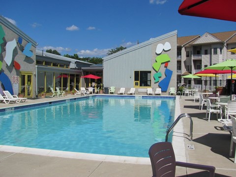 Pool with lawnchairs and tables in the center of the community near clubhouse.