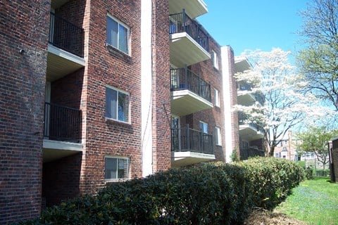 Exterior showing balconies, landscaped grass, and hedges.