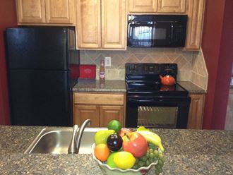 Kitchen with granite counter tops, black appliances and tile backslash - Photo Gallery 2