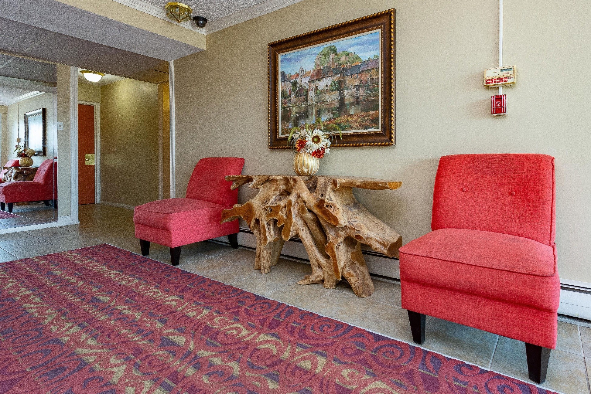 a living room with red chairs and a tree stump table and a painting