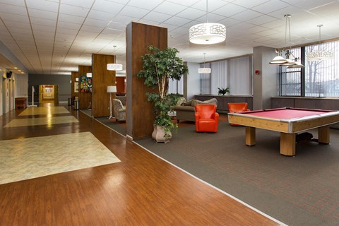 Lounge with pool table, seating, and a large television set.