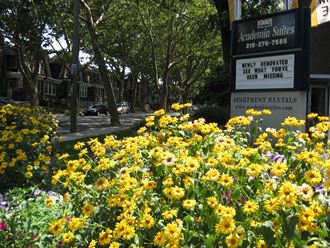 Exterior of property entrance with sign and flowers.