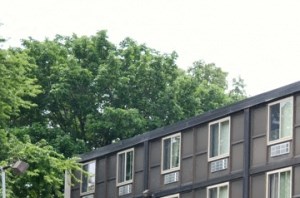 Exterior of building showing parking lot, well kept garden, entrance, and flower pots.