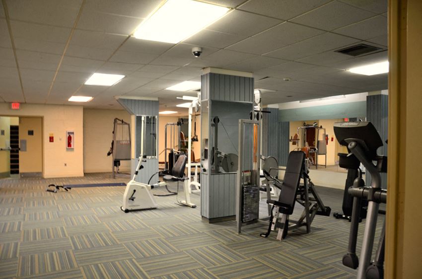 Fitness center equipped with elliptical, weight lifting machines, and indoor exercise bike. - Photo Gallery 1