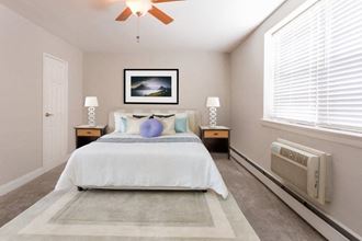 Furnished bedroom with ceiling fan and air conditioner under two windows - Photo Gallery 3