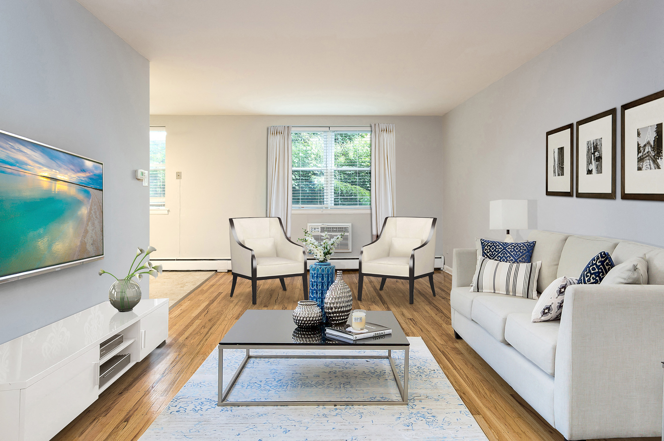 A living room with a white couch, a coffee table, and a painting on the wall.
