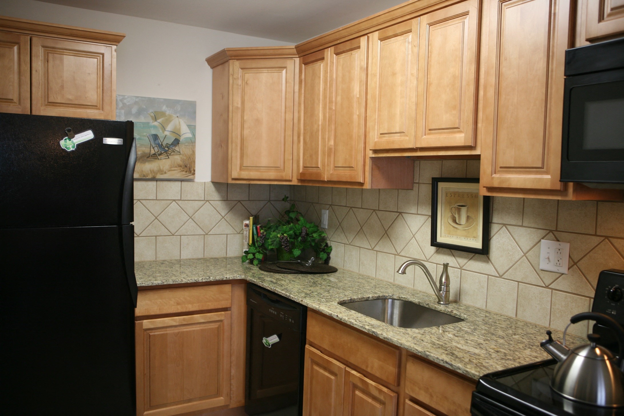 Kitchen with granite counter tops, black appliances and tile backslash