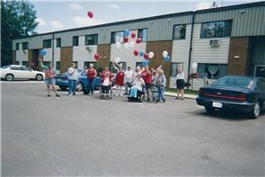 a group of people standing outside of a building with balloons