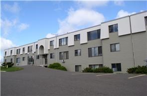 a row of apartment buildings with a parking lot