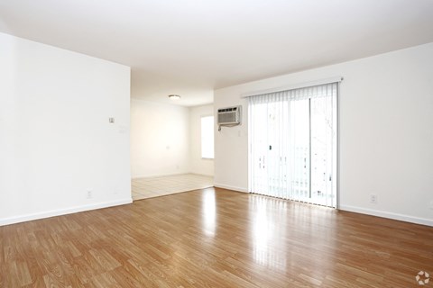 an empty living room with wood floors and a sliding glass door