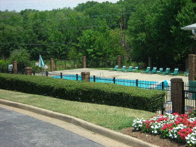 a park with a pool and a fence and flowers