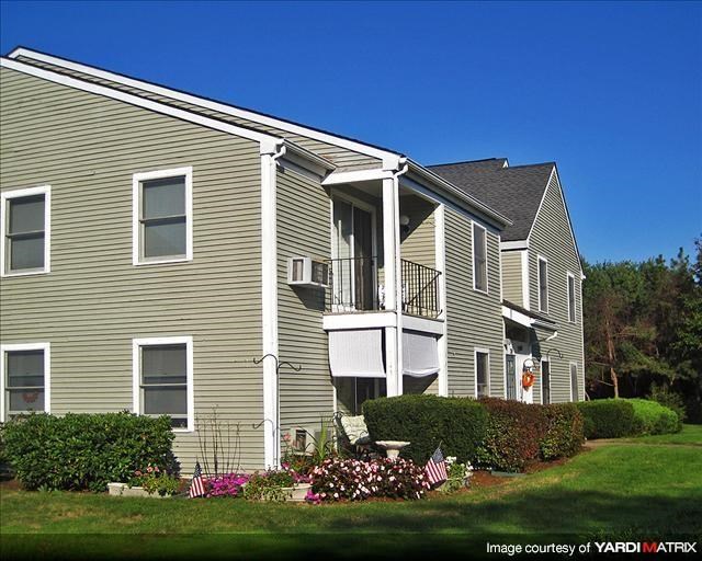a gray house with a balcony and a yard