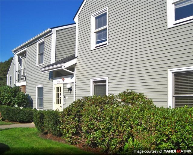 a gray house with bushes in front of it