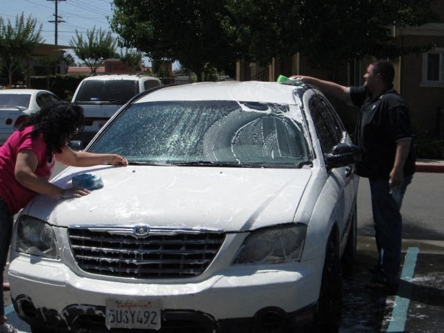 a man and a woman washing the windshield of a car