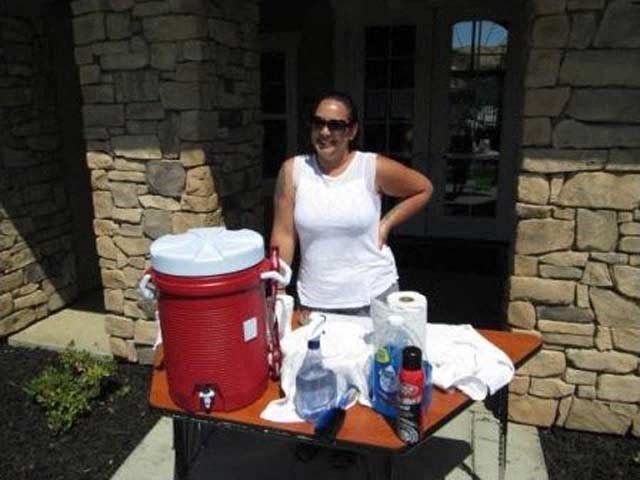 a woman standing next to a table with a red cooler