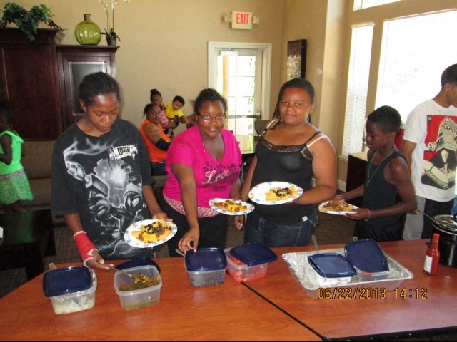 a group of women standing around a table with plates of food