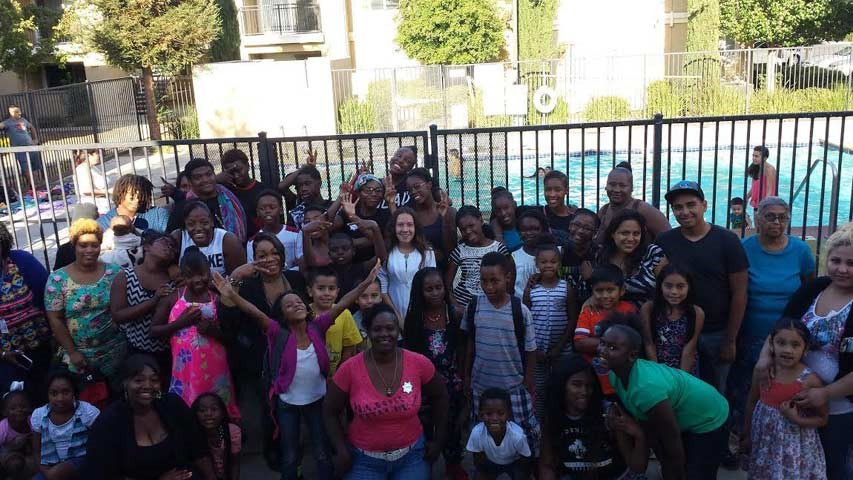 a group of people posing in front of a fence